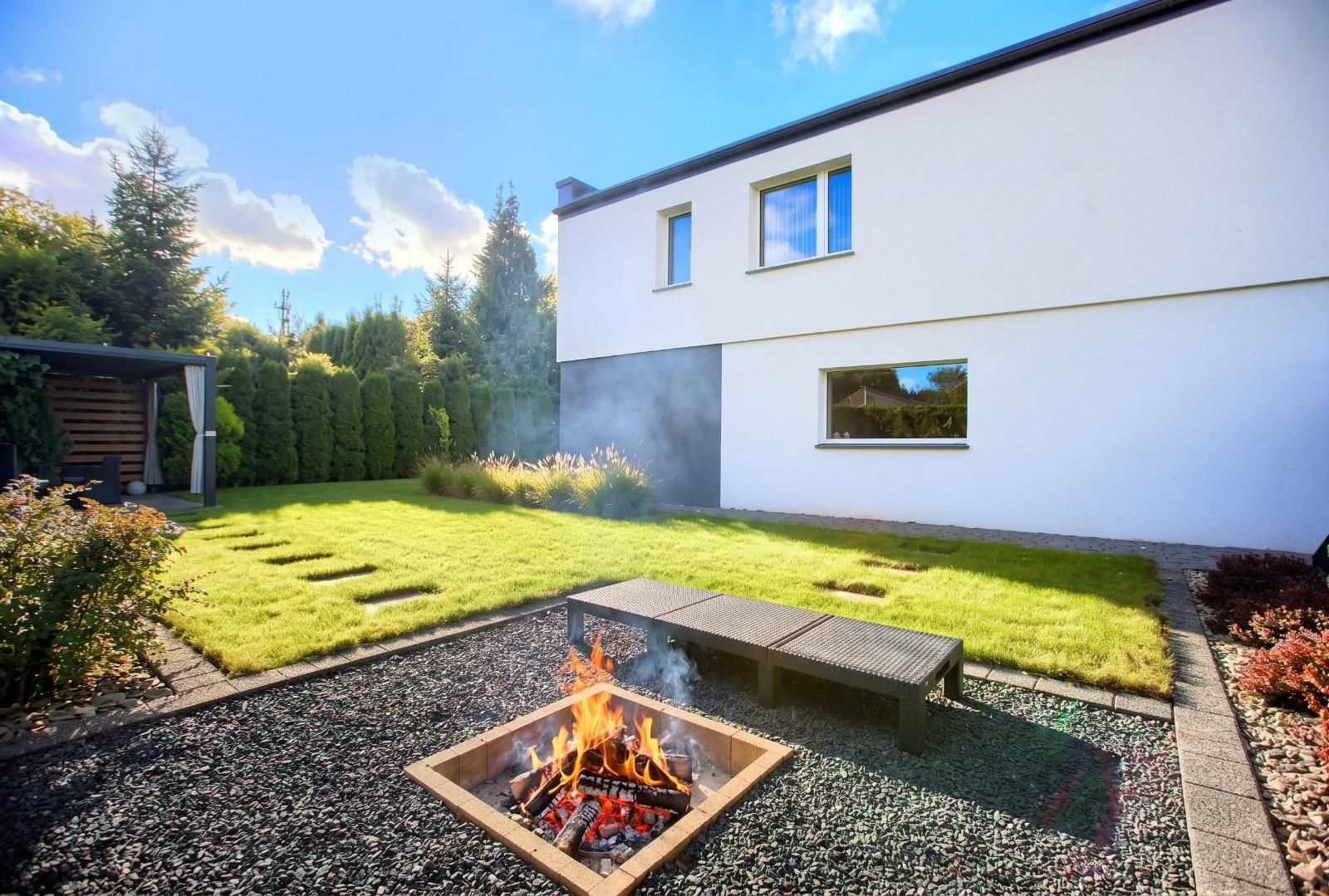 Feuerstelle mit Bank am Haus, Rasen mit Trittplatten