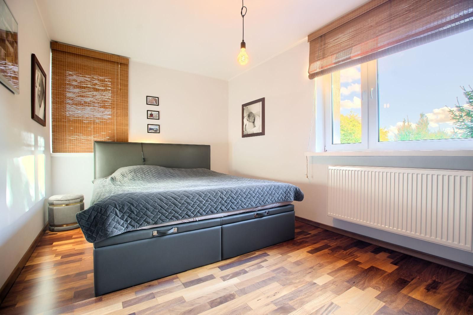 Schlafzimmer mit Doppelbett, Parkett und Fenster ins Grüne