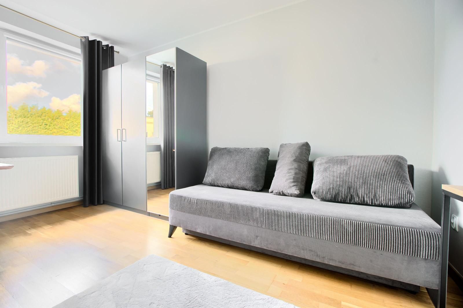 Helles Zimmer mit Sofa und Kleiderschrank