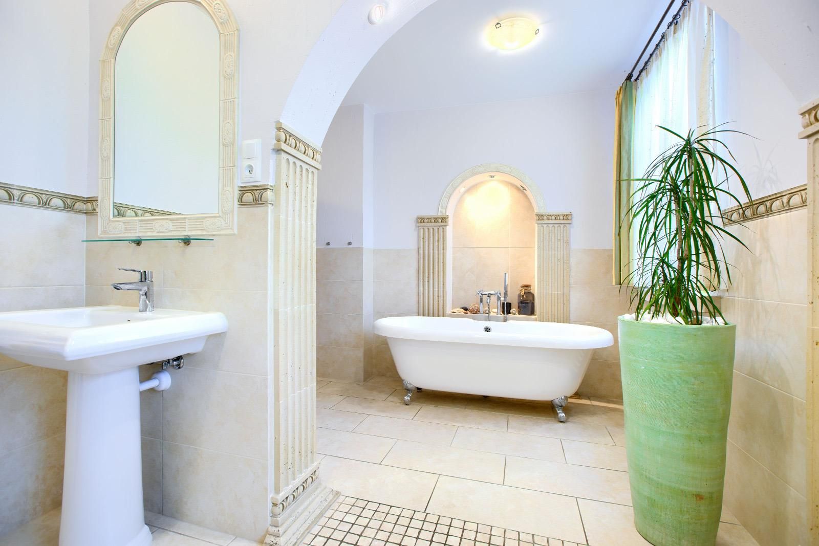 Badezimmer mit freistehender Wanne auf Füßen in einer Bogennische